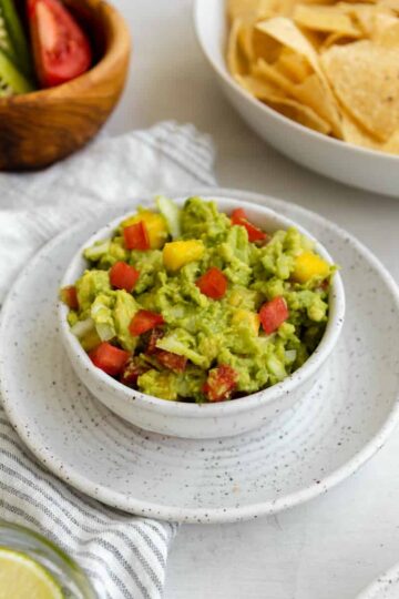 mango guacamole in a bowl with tomatoes.