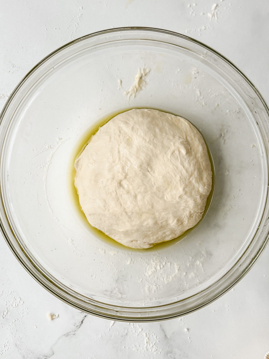 Small ball of pizza dough in a bowl with olive oil