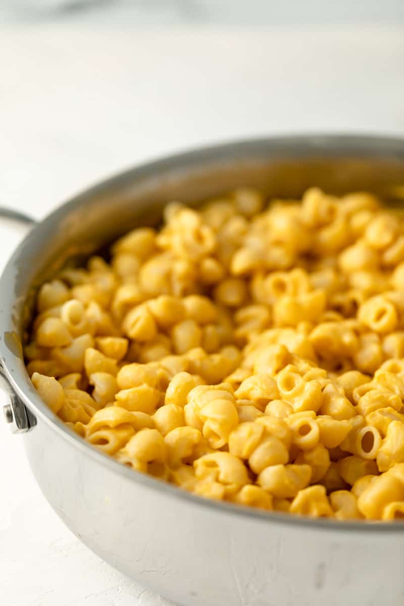 close of of macaroni in velvety butternut squash yellow cheese sauce in a stainless pan