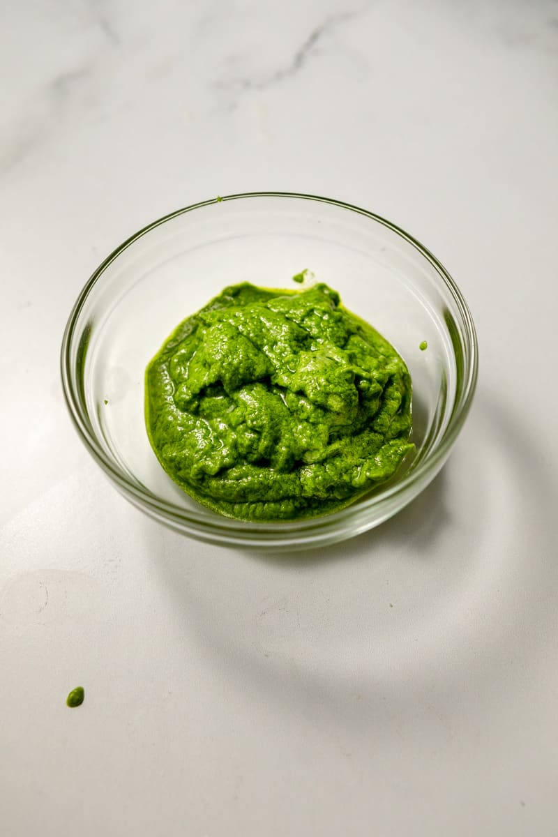 bright green creamy pesto sauce in a glass dish 
