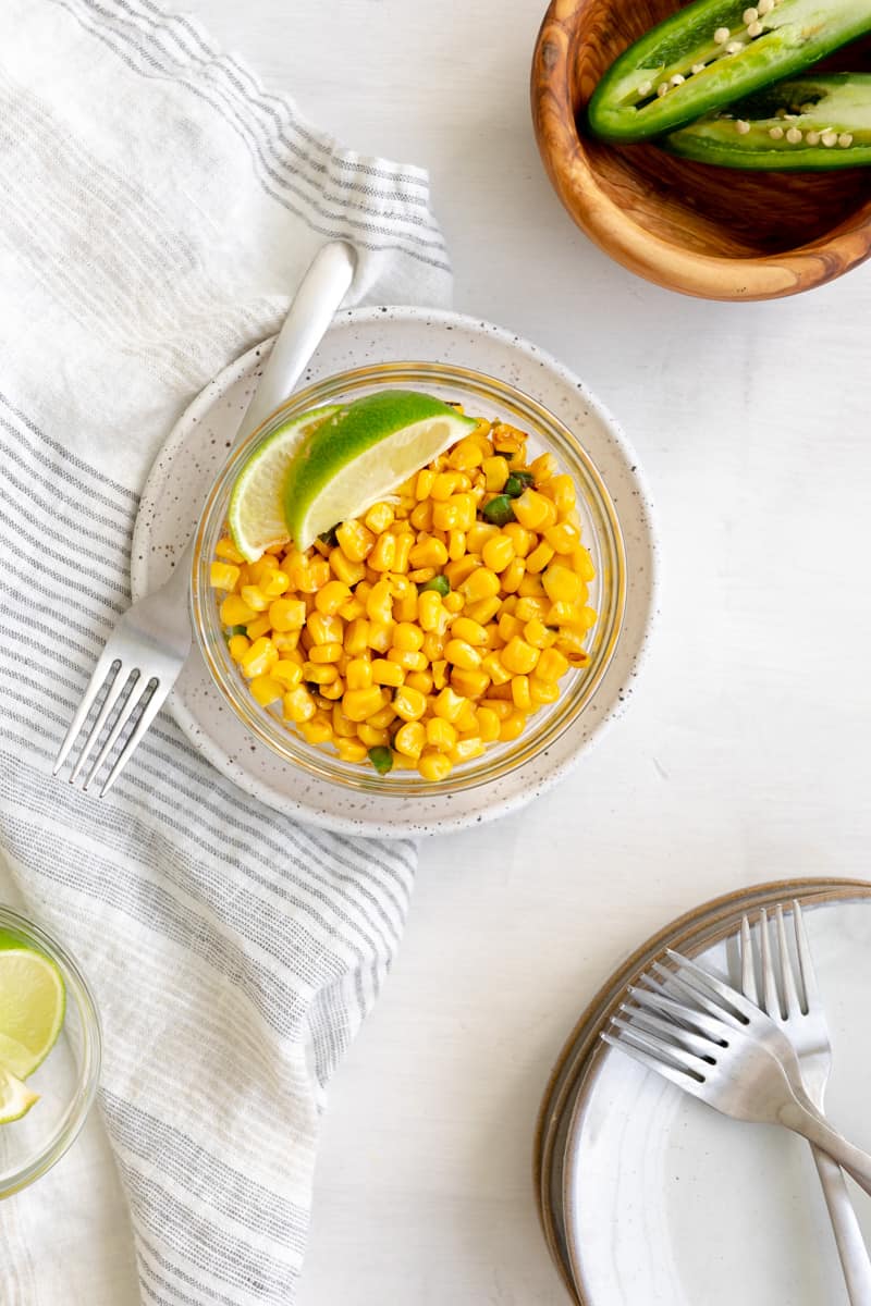 street corn in a bowl with jalapeno bits and lime