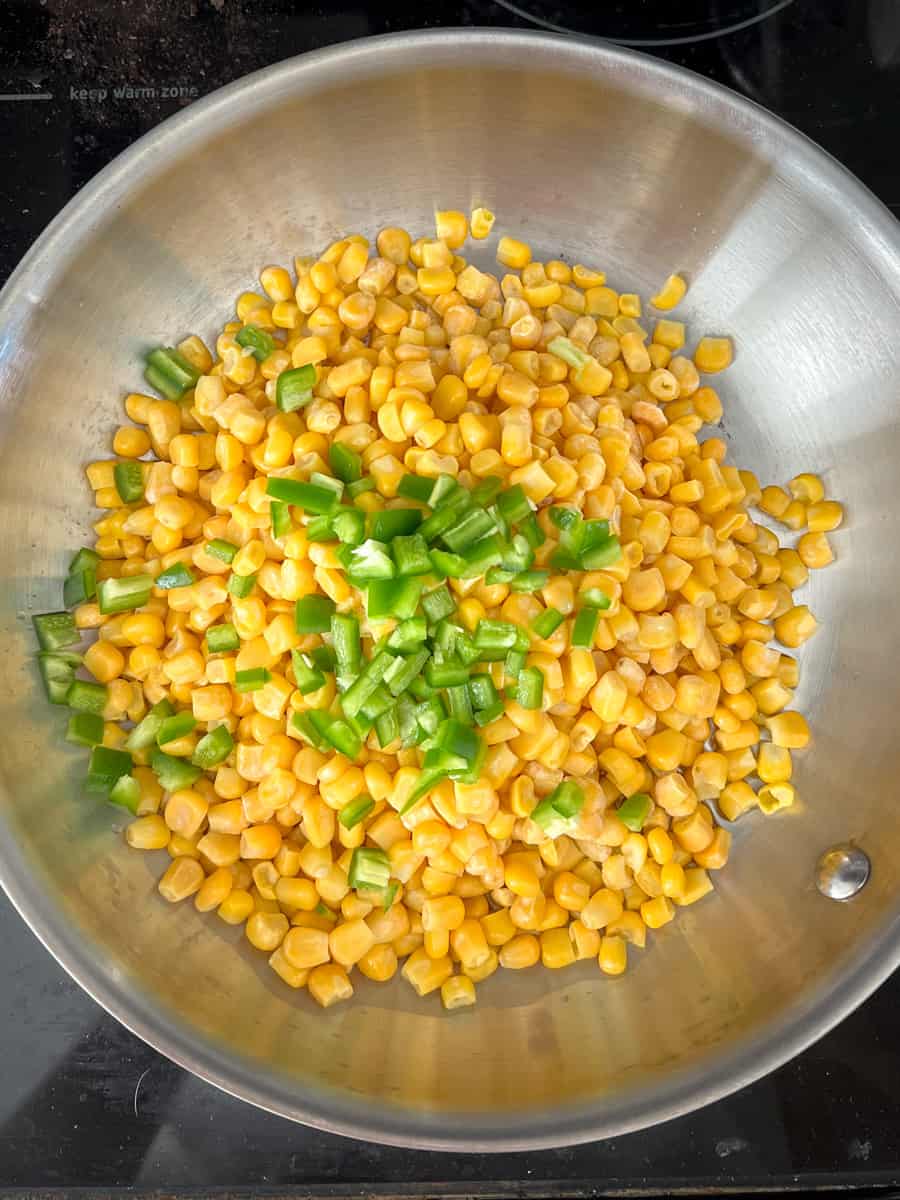 frozen corn kernels in a frying pan with jalapeno pieces