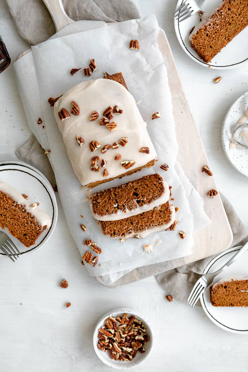 vegan carrot cake loaf topped with icing and chopped pecans