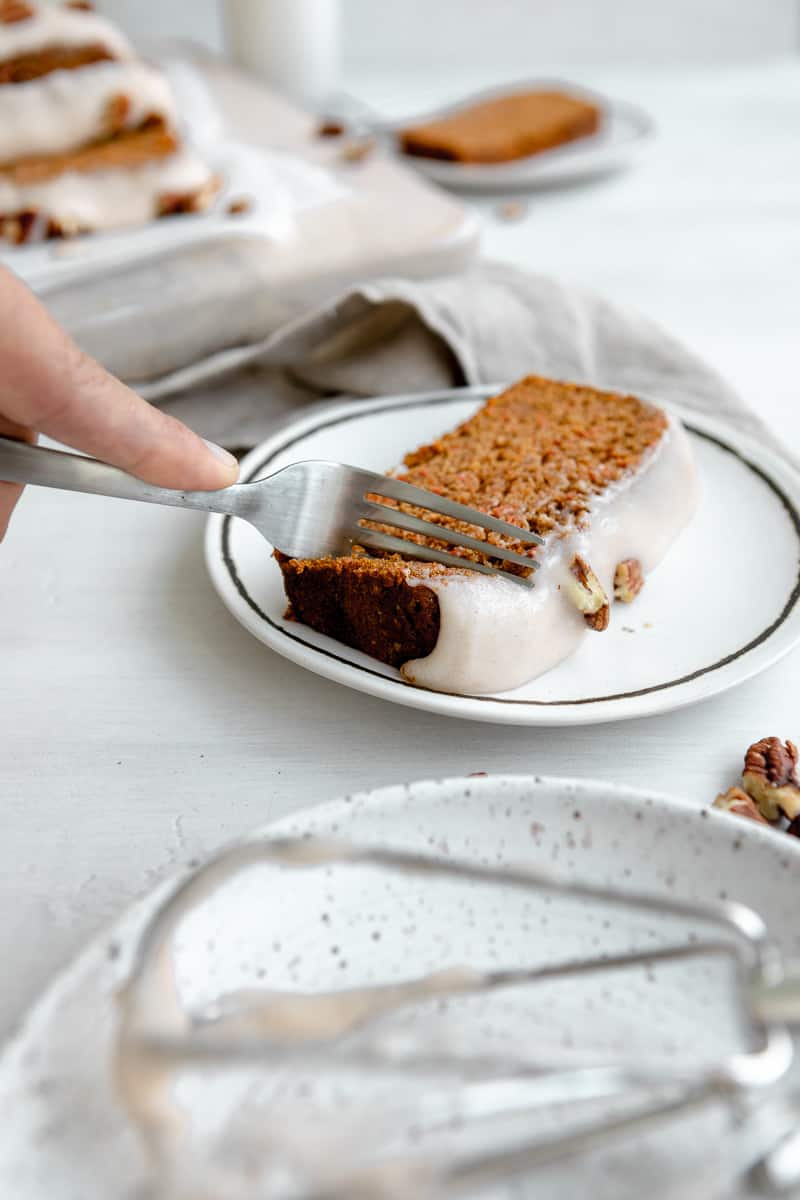 fork cutting into a slice of frosted carrot cake bread