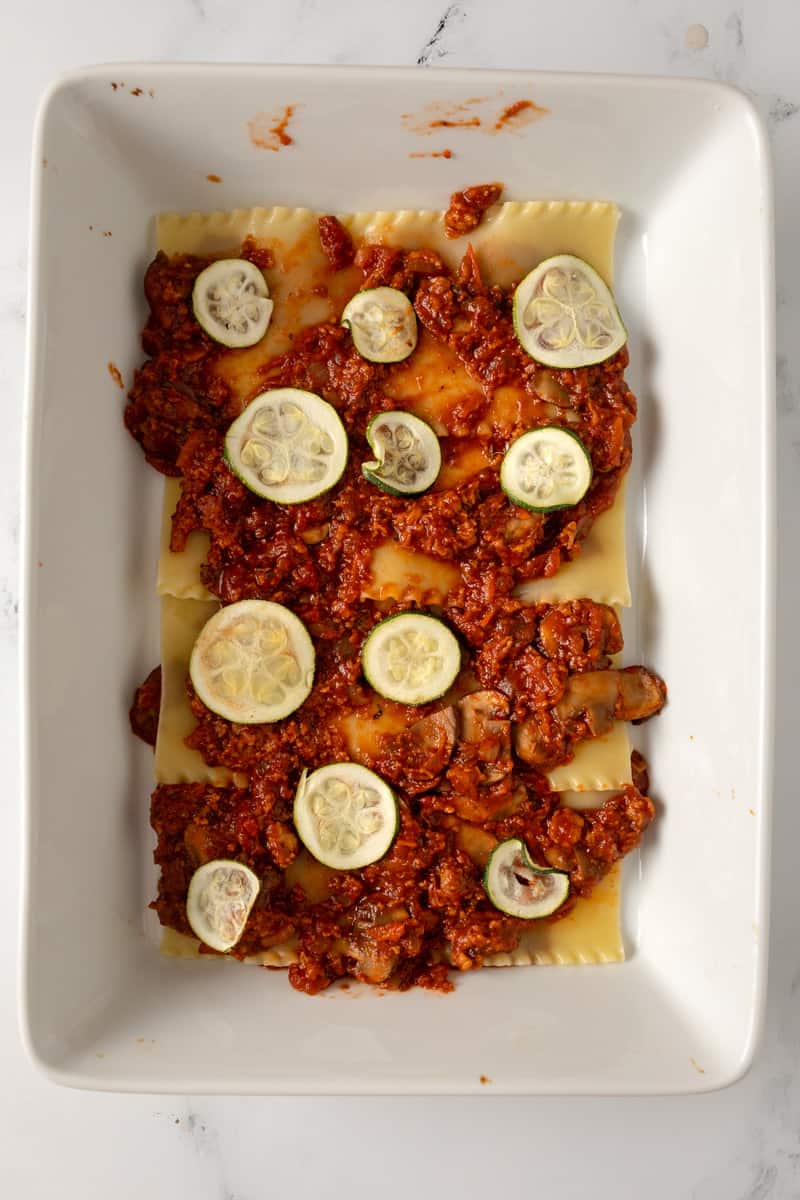 lasagna noodles topped with sauce and zucchini
