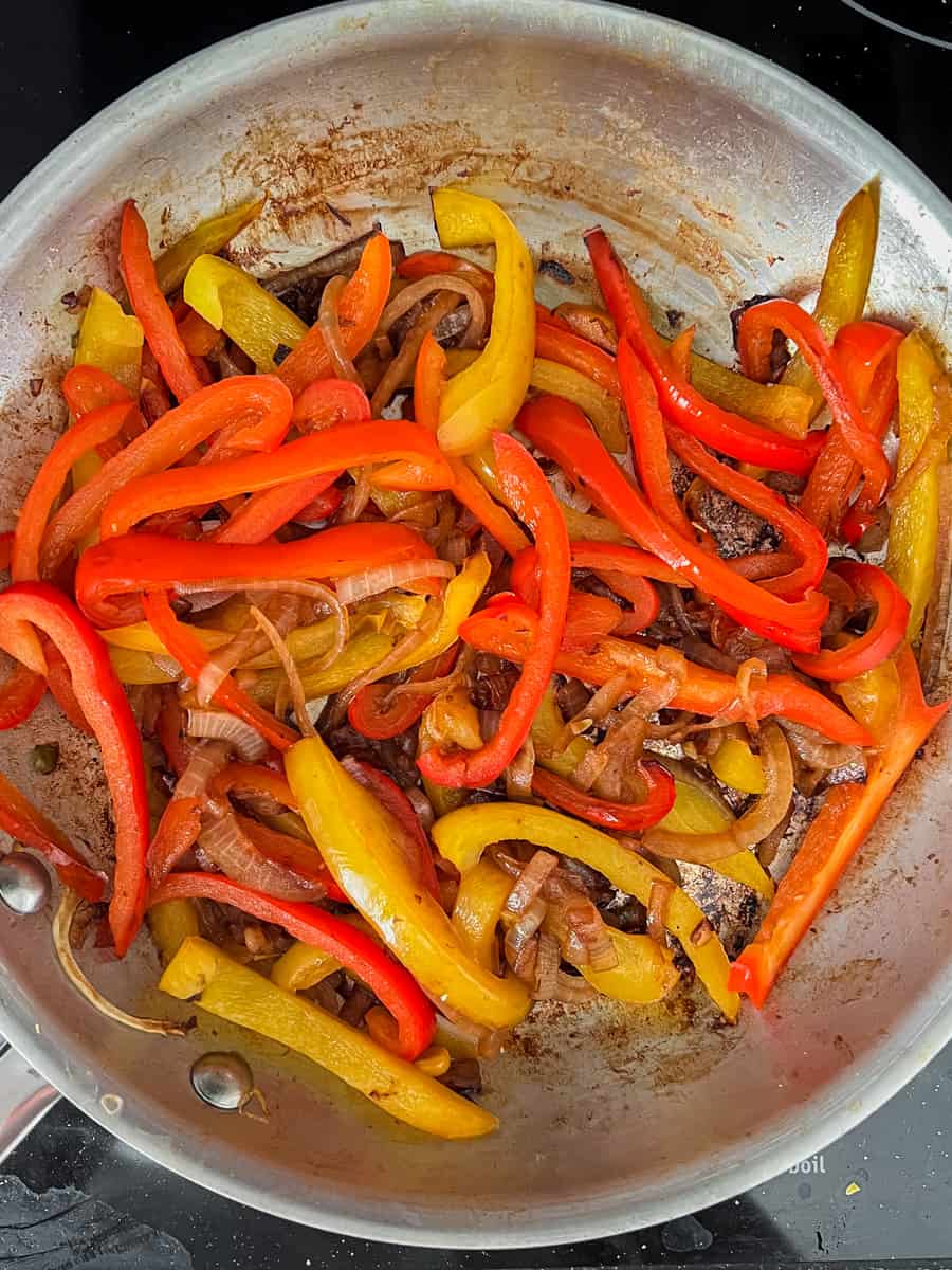 soft red and yellow bell peppers and slightly caramelized onions in a frying pan