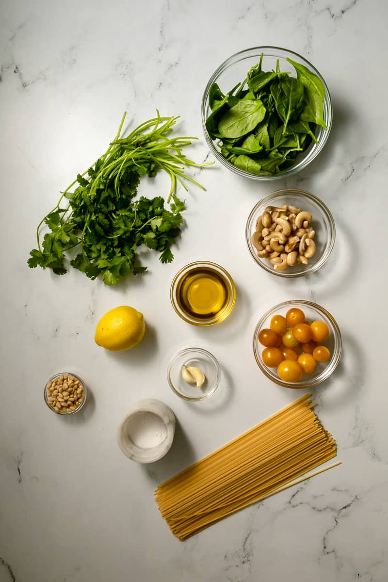 ingredients for pesto pasta with veggies in glass bowls