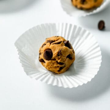 vegan cookie dough ball on a cupcake wrapper with chocolate chips.