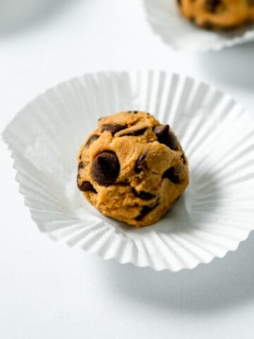 vegan cookie dough ball on a cupcake wrapper with chocolate chips.