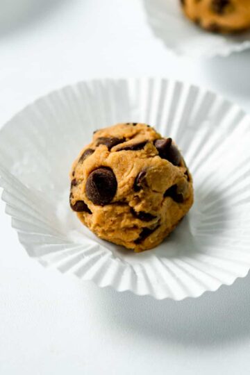 vegan cookie dough ball on a cupcake wrapper with chocolate chips.