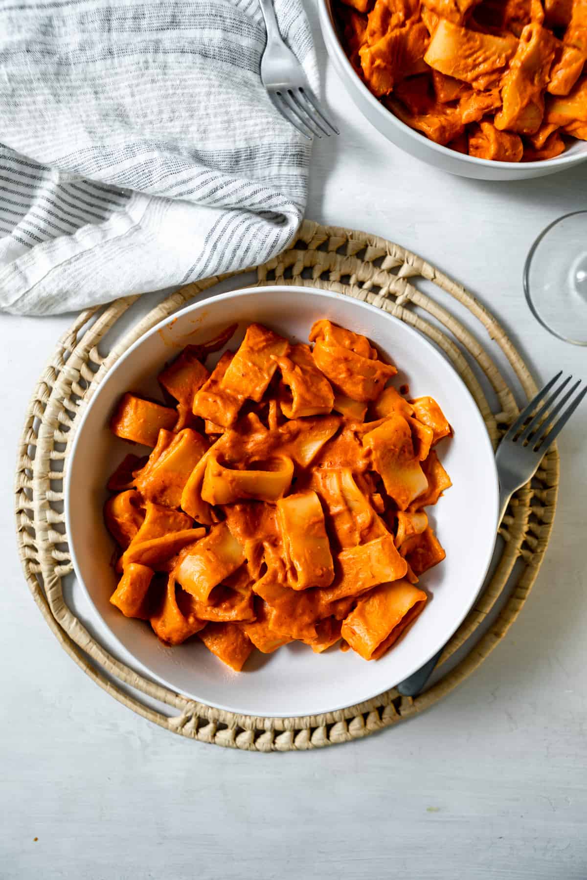 rigatoni coated in thick, creamy red vodka sauce, with a fork and linen napkin. 