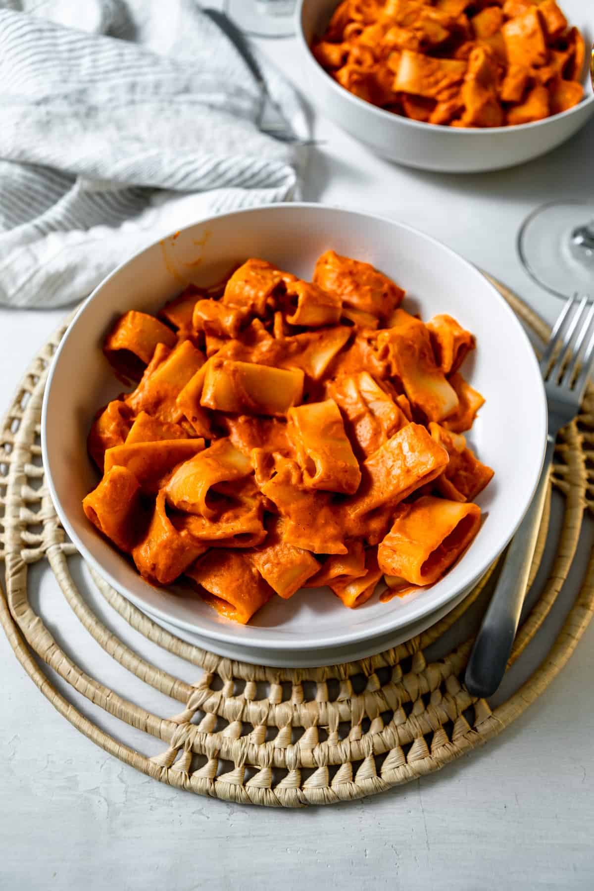 bowl of rigatoni with vodka sauce with a fork and a glass of wine. 