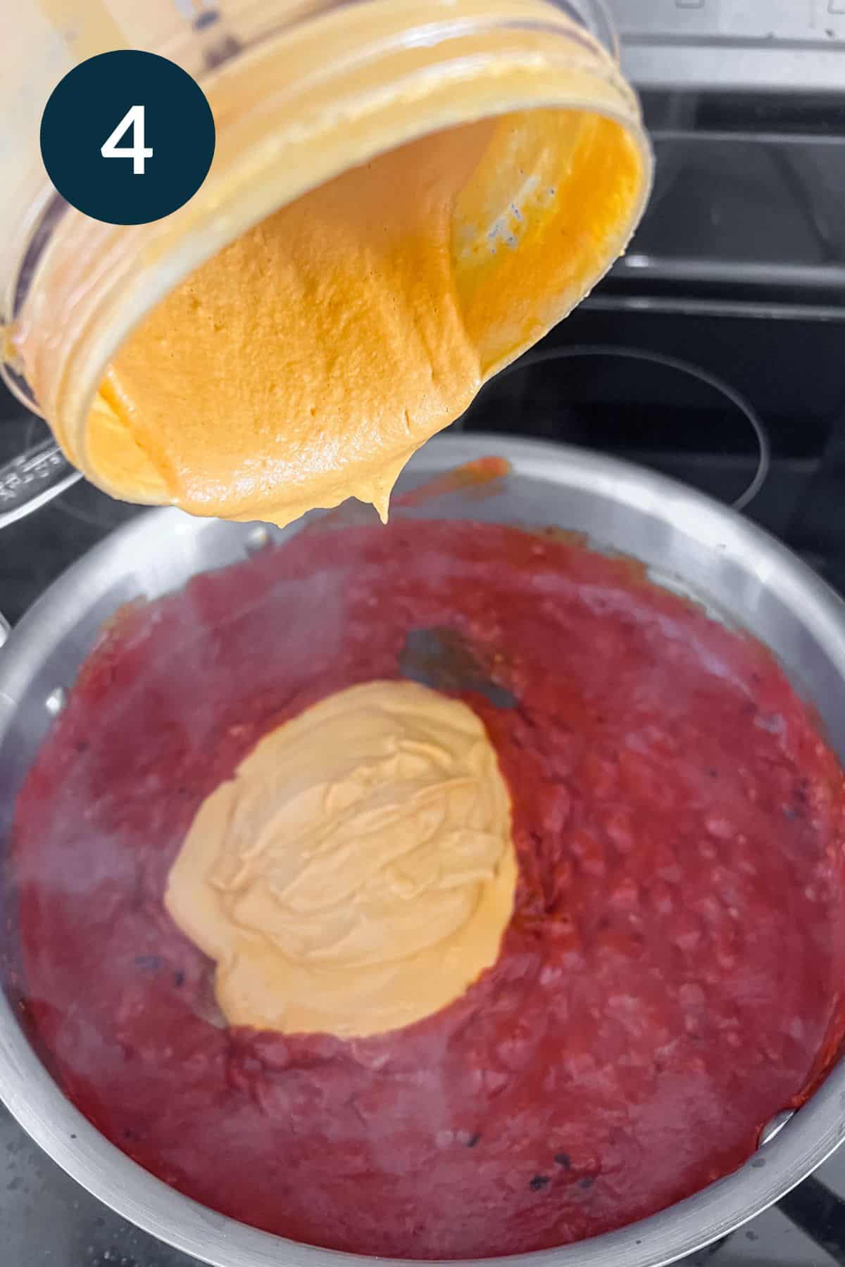 pouring cashew cream sauce into pan with red sauce.