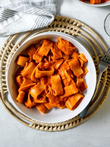 rigatoni covered in red vodka sauce in a bowl with a fork.