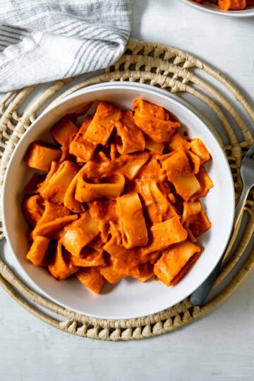 rigatoni covered in red vodka sauce in a bowl with a fork.