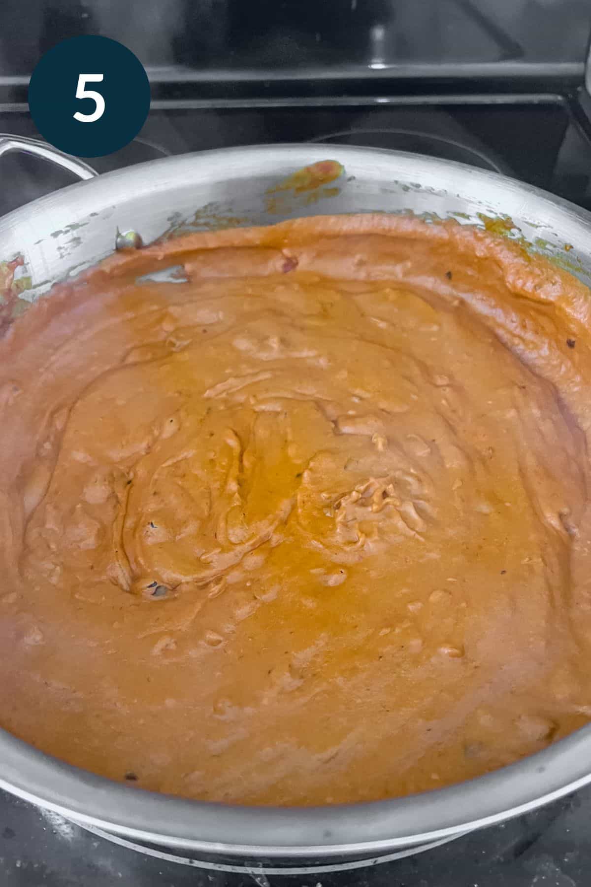 thick orangey red vodka sauce simmering in pan.